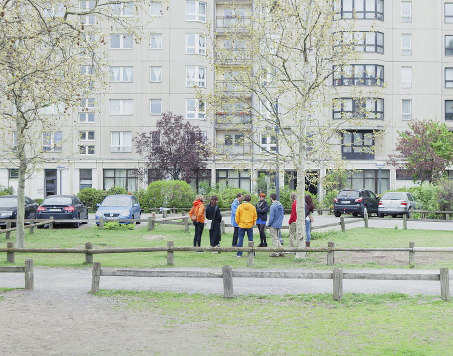 Photo of a group of people standing together on a patch of grass in an urban area