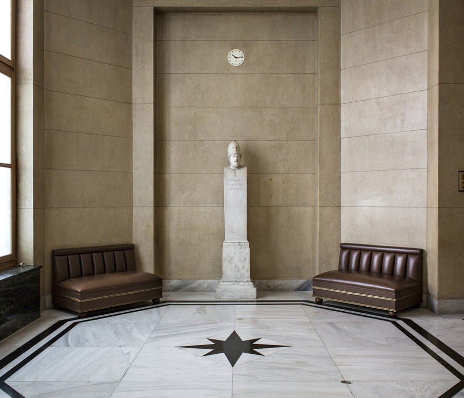 A grand hallway in the Greek parliament with a statue. 
