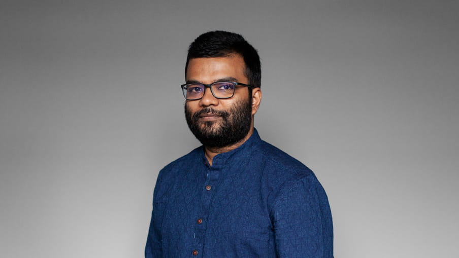 Photo of a man with a beard and glasses - Tanmoy Goswami - against a grey background.