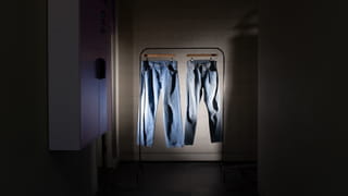 Picture of two jeans hanging on a rack, a spotlight lighting them