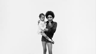Photo of a young girl holding a little child meanwhile pressing the shutter of a remote camera for a portrait.