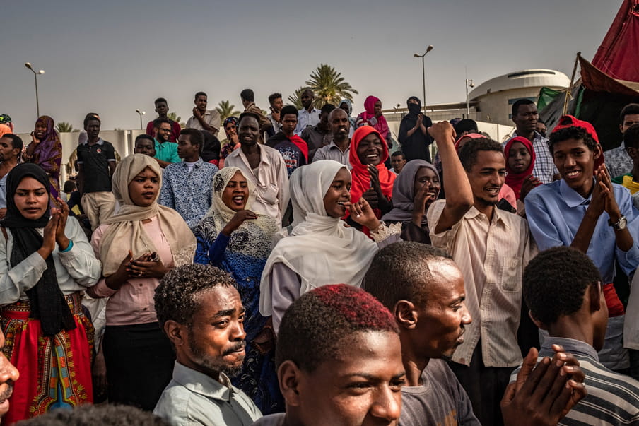 Photo of a group of people in the street, smiling and clapping.