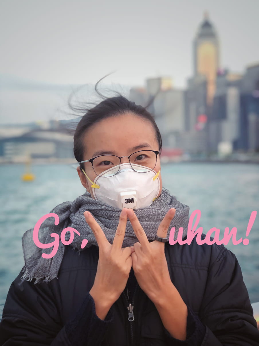 A picture of Yuli Yang wearing a mask and making a W - for Wuhan - with her fingers. The words "Go Wuhan" are inscribed across the picture.
