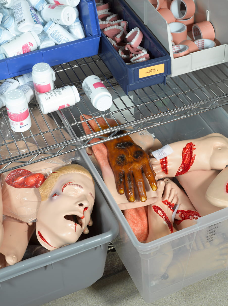 Photo of a closet with containers holding plastic heads, teeth, feet and hands. 