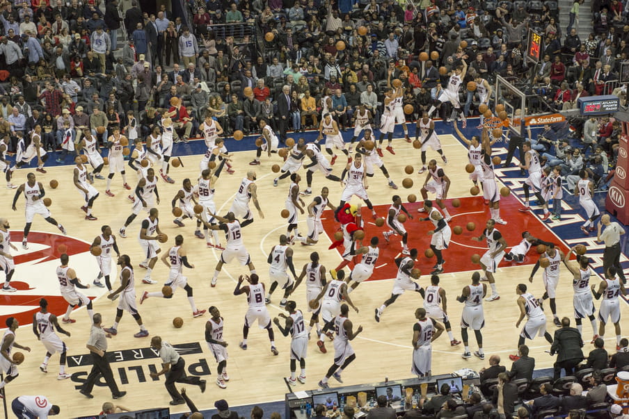 Photo-montage of a basketball field, heavily crowded with men playing.