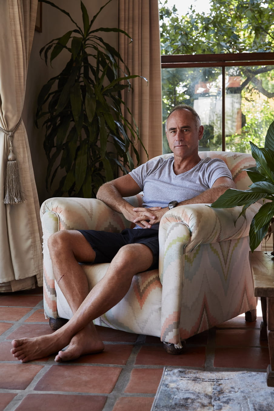 Photo of a man sitting on a large chair, inside a house