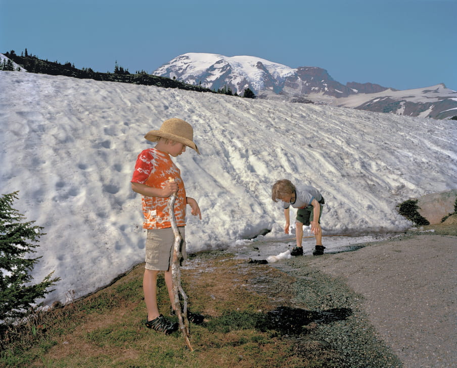 Photo of two boys playing, a mountain full of snow behind them