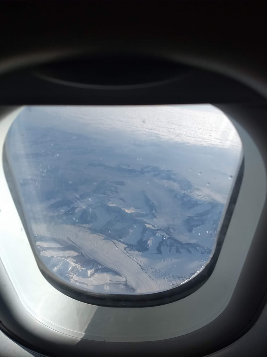 A view out an airplane window high above a glacier in Greenland.