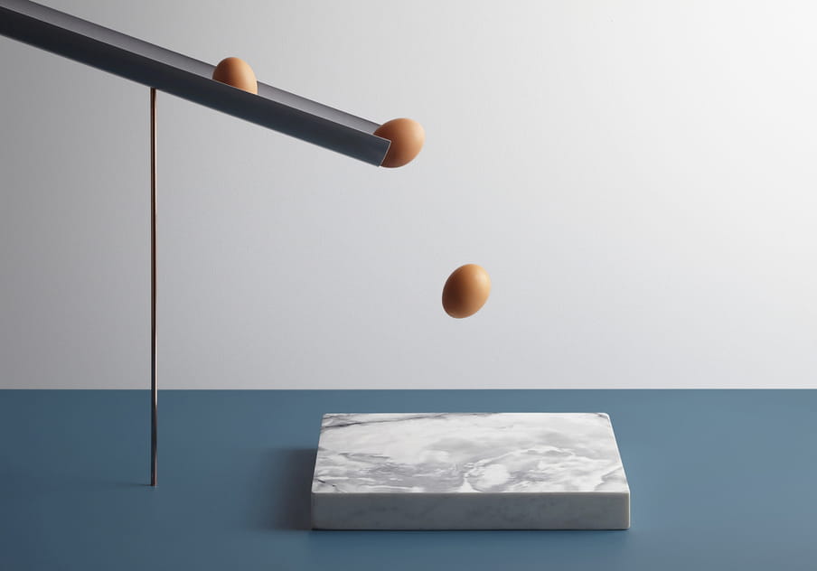 Colour photograph of a rock eggs about to fall on a piece of marble.