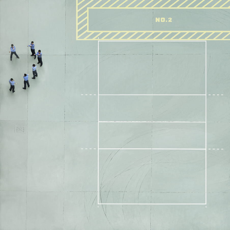 Photograph taken from above of men in blue shirts and black pants stretching on a mint green cour