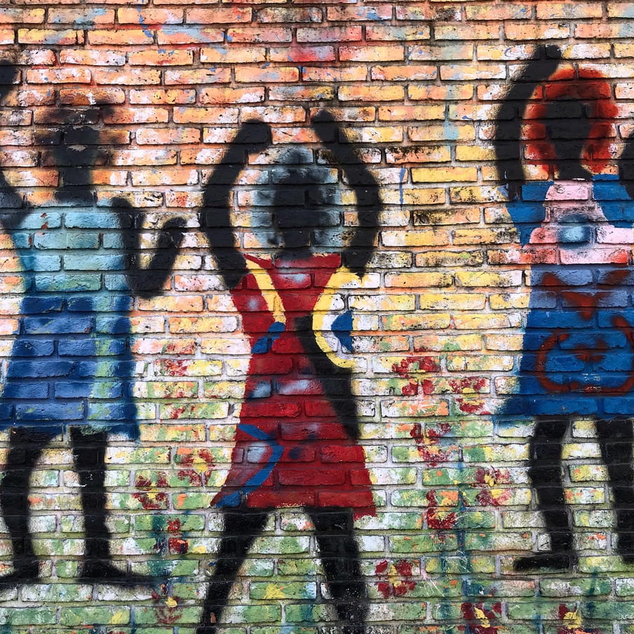 A graffiti with the drawings of three black women with their arms raised.