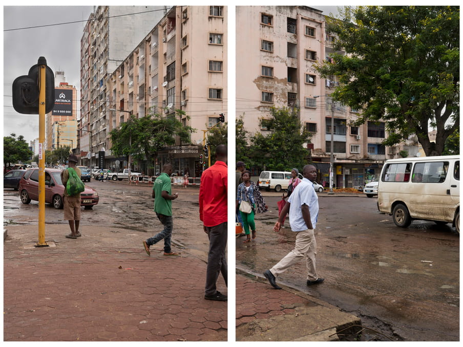 An image of people crossing the road. In the background a decaying building and trees lining the sidewalk.