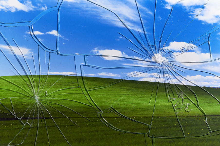 Photograph showing a broken glass in front of a green land and a blue sky.