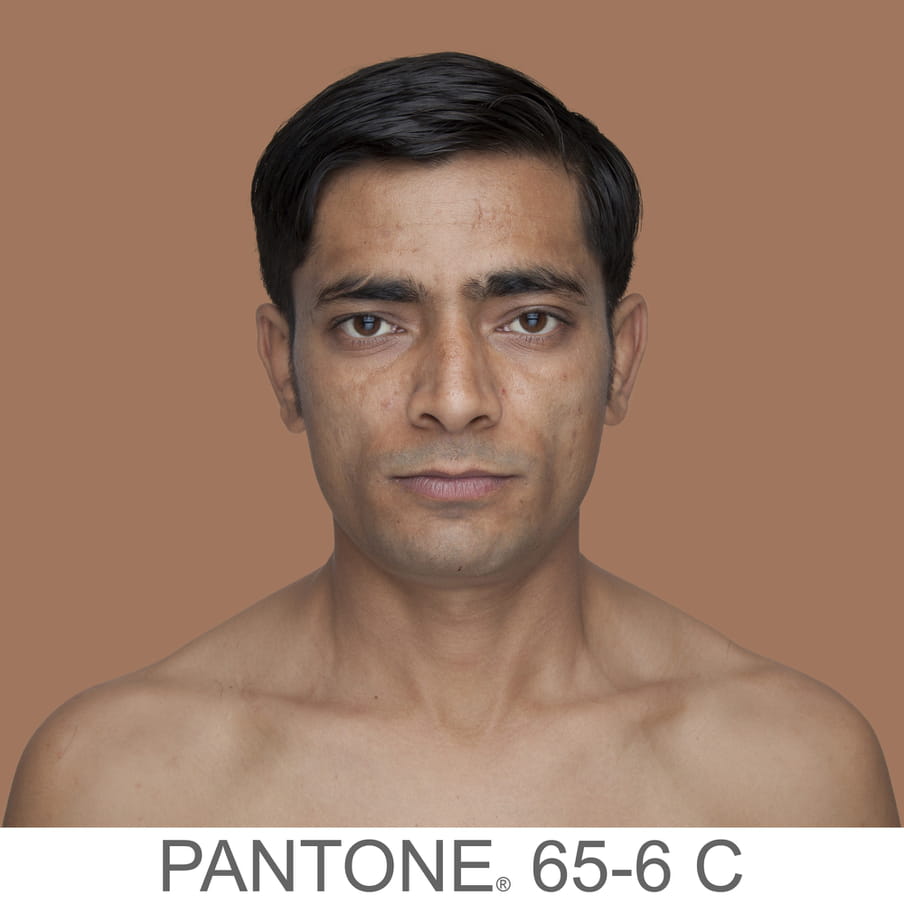 Photographic portrait of a male with short hair and no beard. The background is a sample of 11 x 11 pixels taken from the nose of the subject and matched with the industrial pallet Pantone®. The pantone color is written out as PANTONE 65-6 C.
