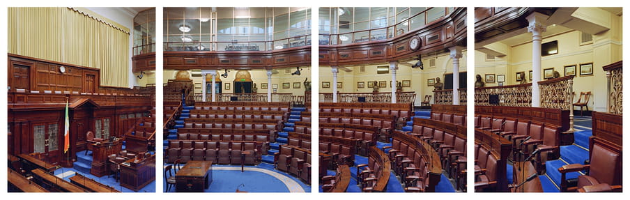 Photograph of large hall with blue carpet and wooden chairs