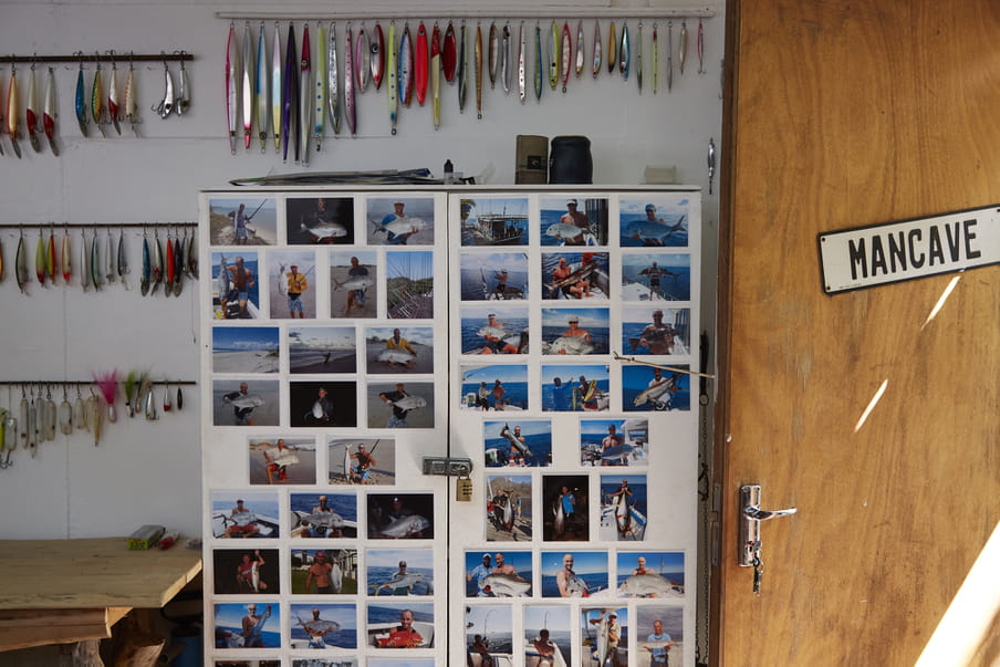 A wall full of fishing equipment and photos of Paddy fishing on the wall. On the door it says ‘Mancave’