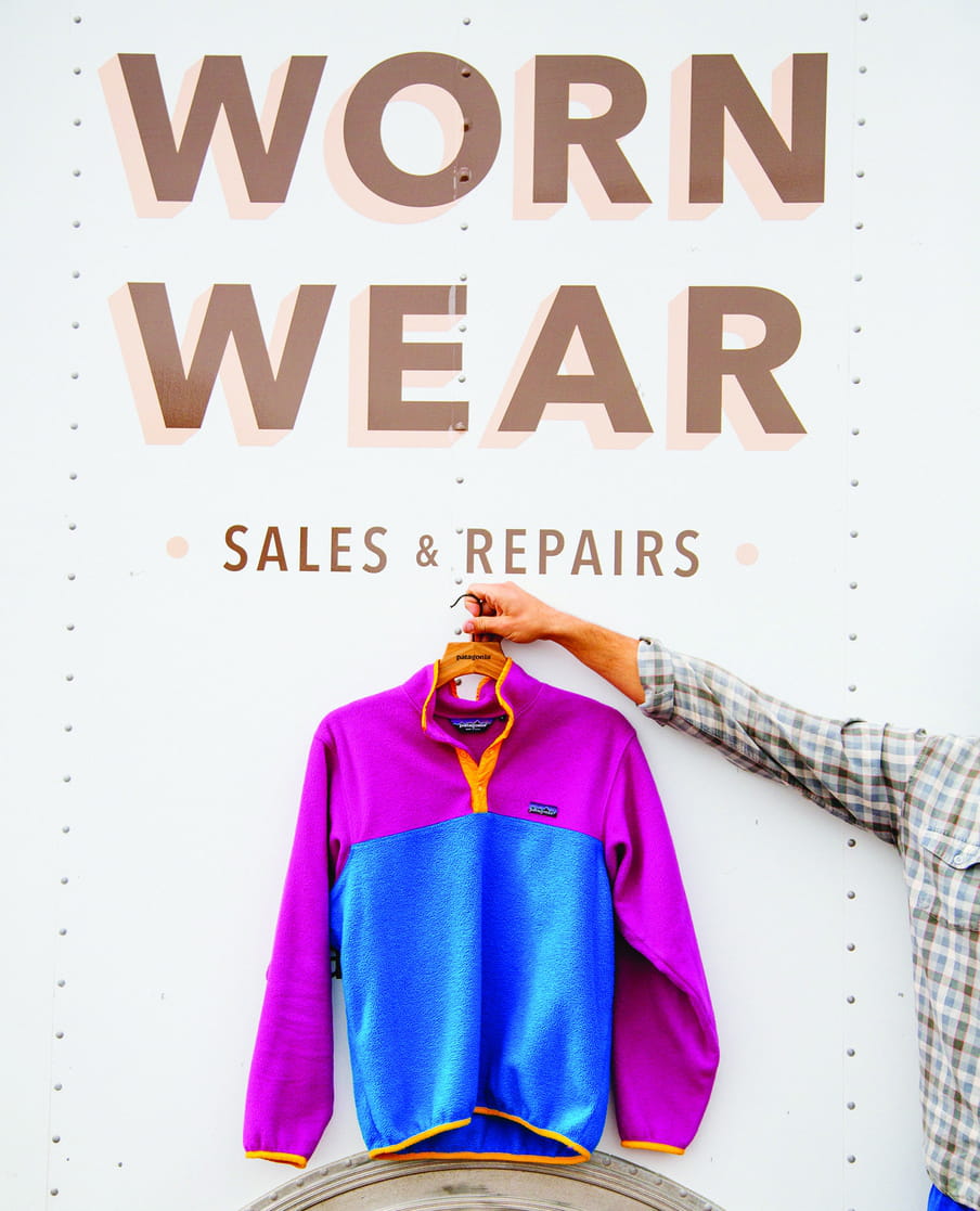 Photo of an arm holding up a sweatshirt with the text on a wall above it stating: "Work Wear Sales & Repair"