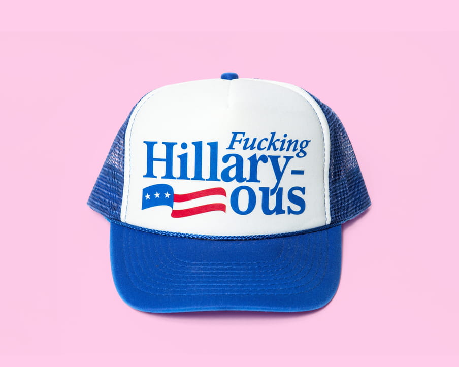 Photo of a cap with the text ‘Fucking Hillaryous’ on a pink background