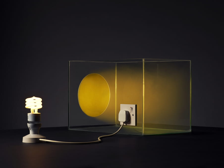 Photo of a lit lamp connected to a glass tank, an artificial sun shining in it