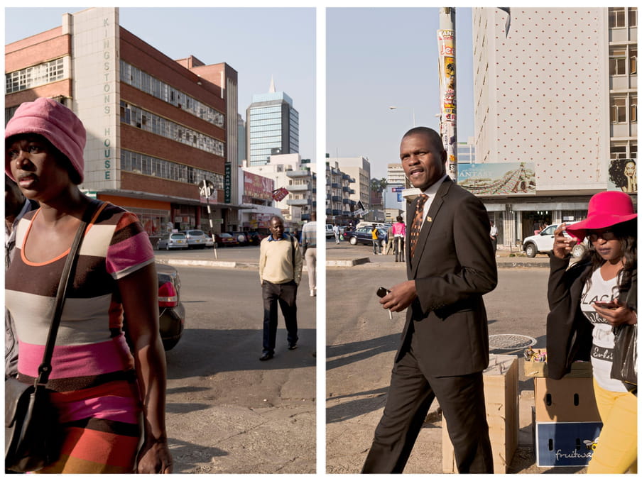 An image of people walking across a street. In the front a woman wearing a colourful dress and a man in a suit. In the background a large building with a sign saying "Kingstons House" and parked cars.