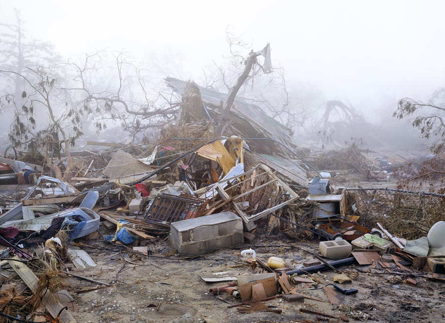 Photo of a destroyed house, not much of it left, against a misty background