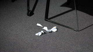 Photo of folded paper planes on a carpeted floor