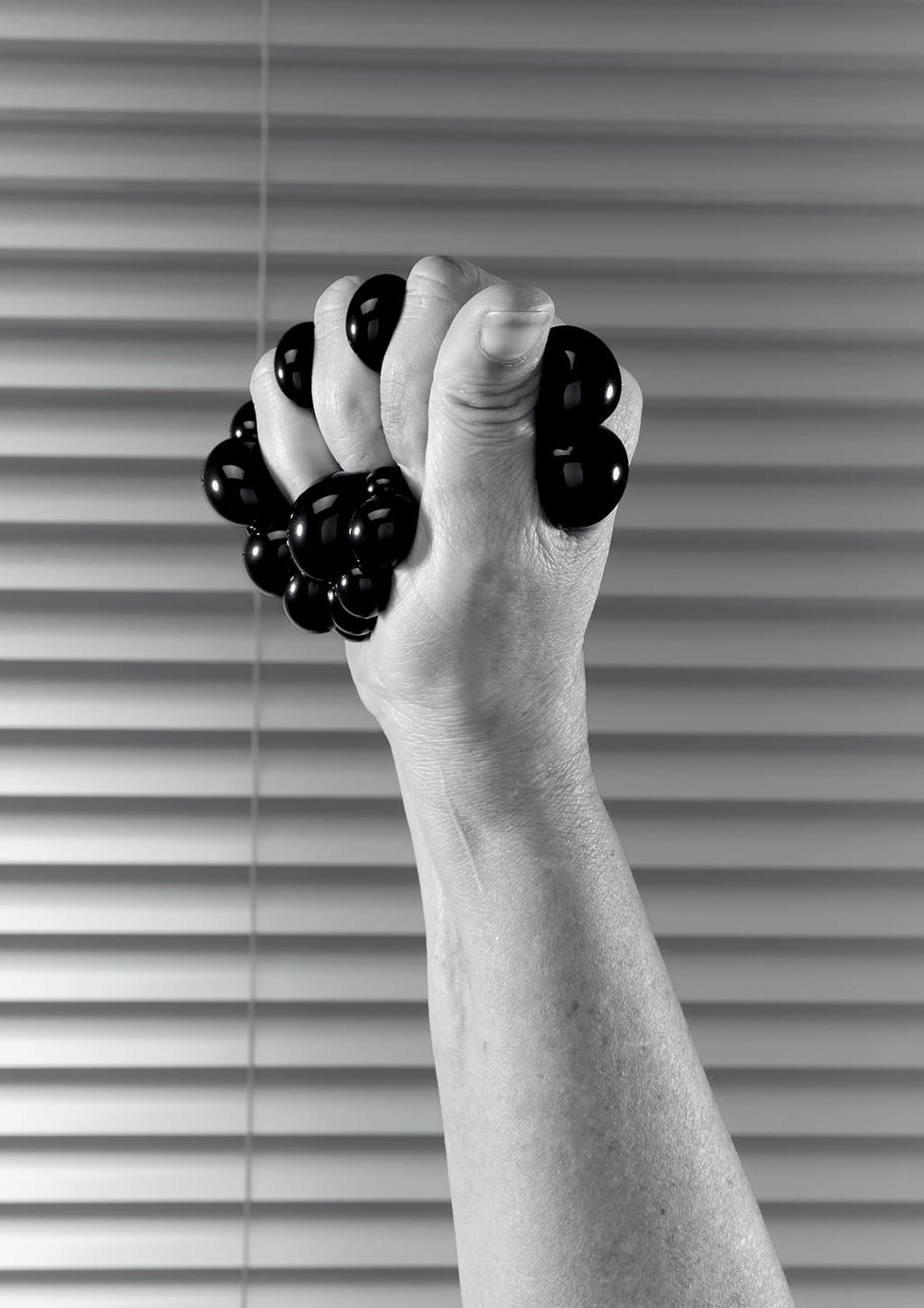 Black and white photograph of a hand squeezing a black thing.