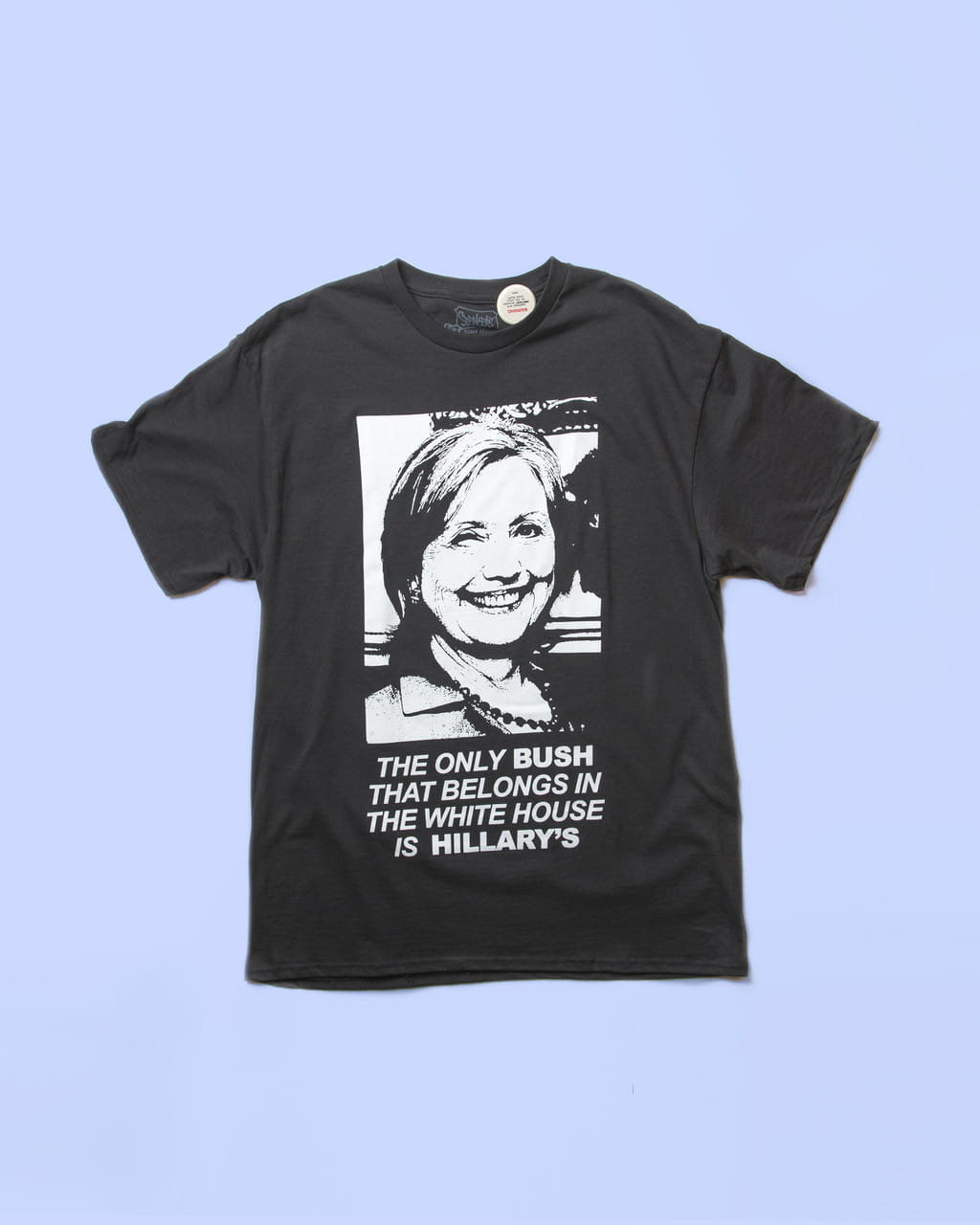 Photo of a T-shirt with a black and white photo of Hillary Clinton stating ‘The only Bush that belongs in the white house is Hillary’s’ on a purple background