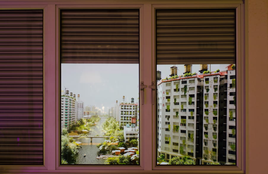 Photo of a fake window showing buildings with windmills on top of them and many, many plants