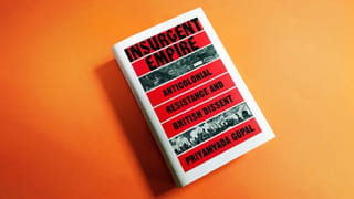 Photograph of a book laying on an orange background. The cover is white, with red stripes where the following text appears in black: Insurgent Empire, anticolonial resistance and British dissent, Priyamvada Gopal. Two stripes show black and white engraving, one of a house, the other one of a group of people with weapons.