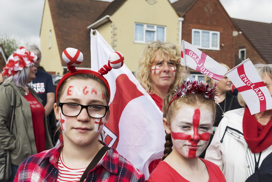 Photo of a group of people with English flags in their hands and painted on their faces.