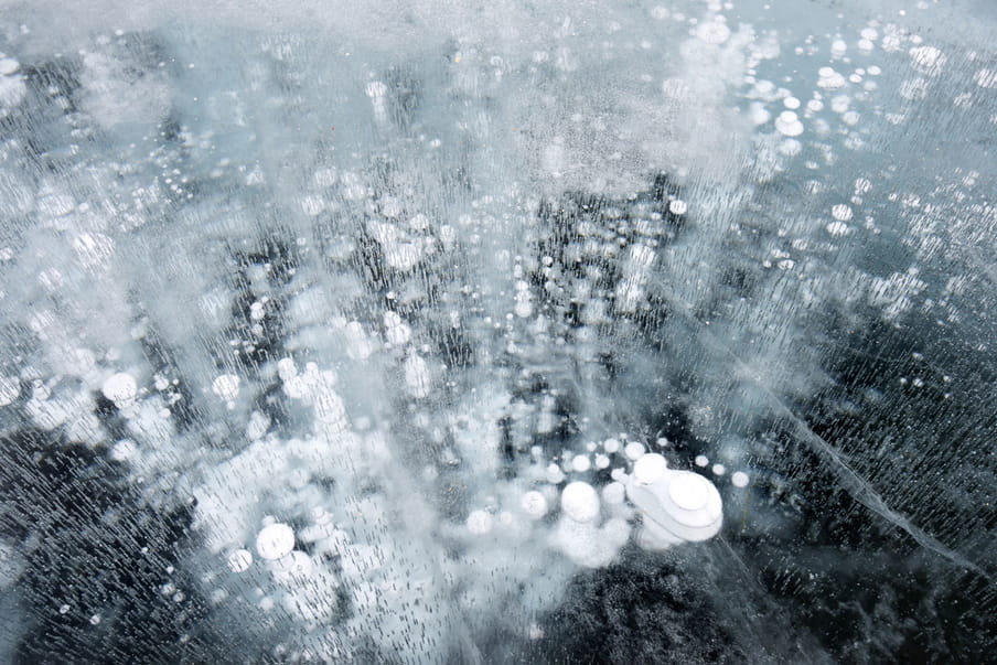 Image with a perspective looking down on white circular and oval looking shapes, with the seeming texture of a cloud, and other white circles and lines on a dark blue back ground. They seem to be emitting upwards as gases or fogs