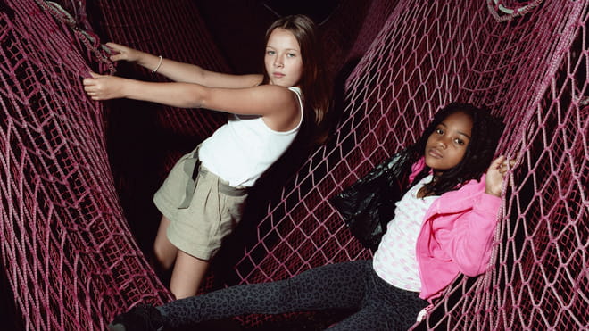 Photo of two young girls playing inside a pink net