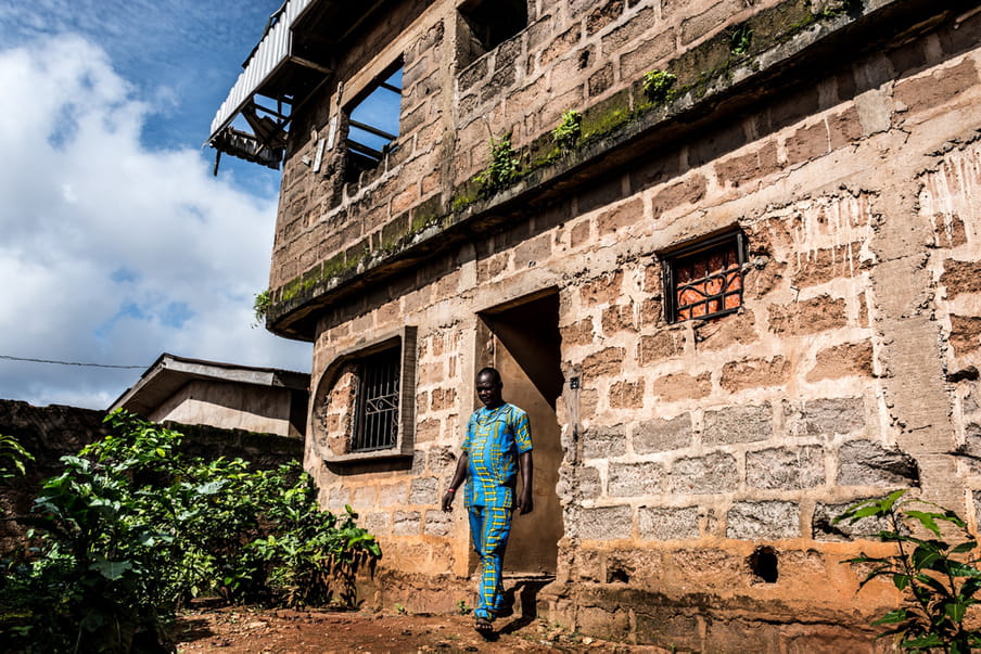 Photo of a man walking out of a house built out of large stone bricks