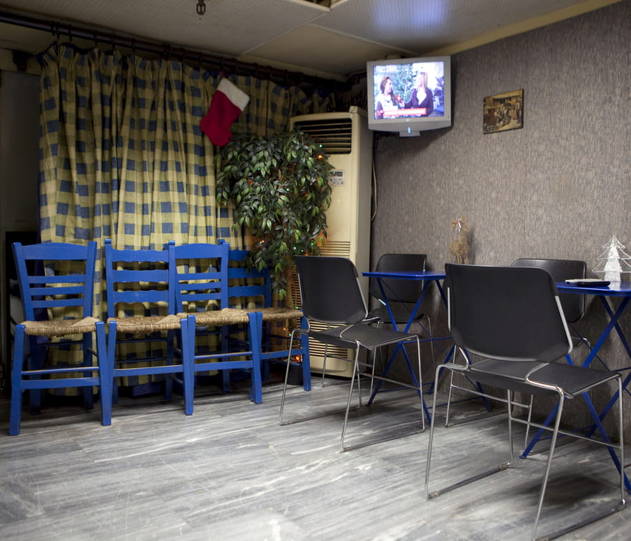 An empty canteen room with a television playing in the corner. A few doleful-looking Christmas have been placed around the room. 