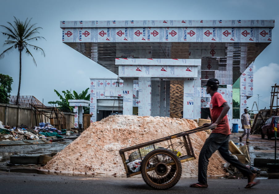 Photo of a man walking with a cart in front of a house under construction