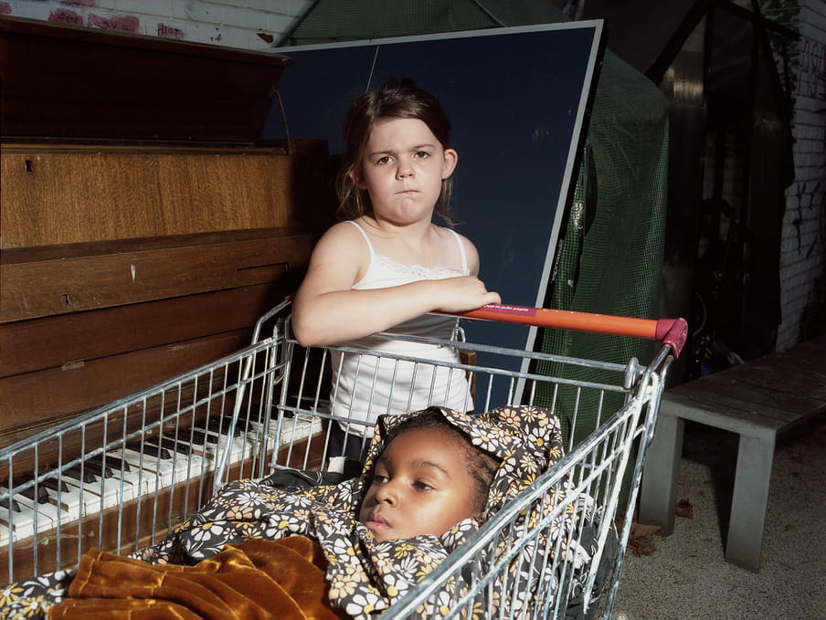 Photo of two kids playing with a shopping cart.