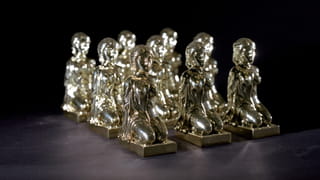 Photo of nine similar silver statues of a woman sitting on her knees with her hands on her back