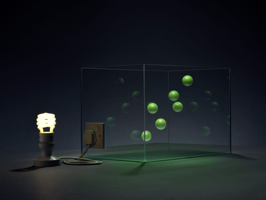 Photo of a lit lamp connected to a glass tank, green little balls floating in it