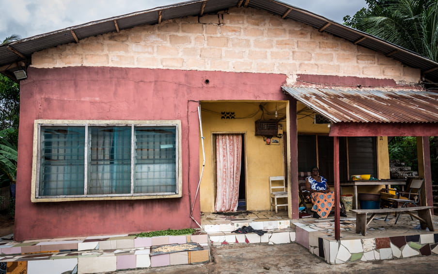 Photo of a woman sitting under a blanket in front of a pink house