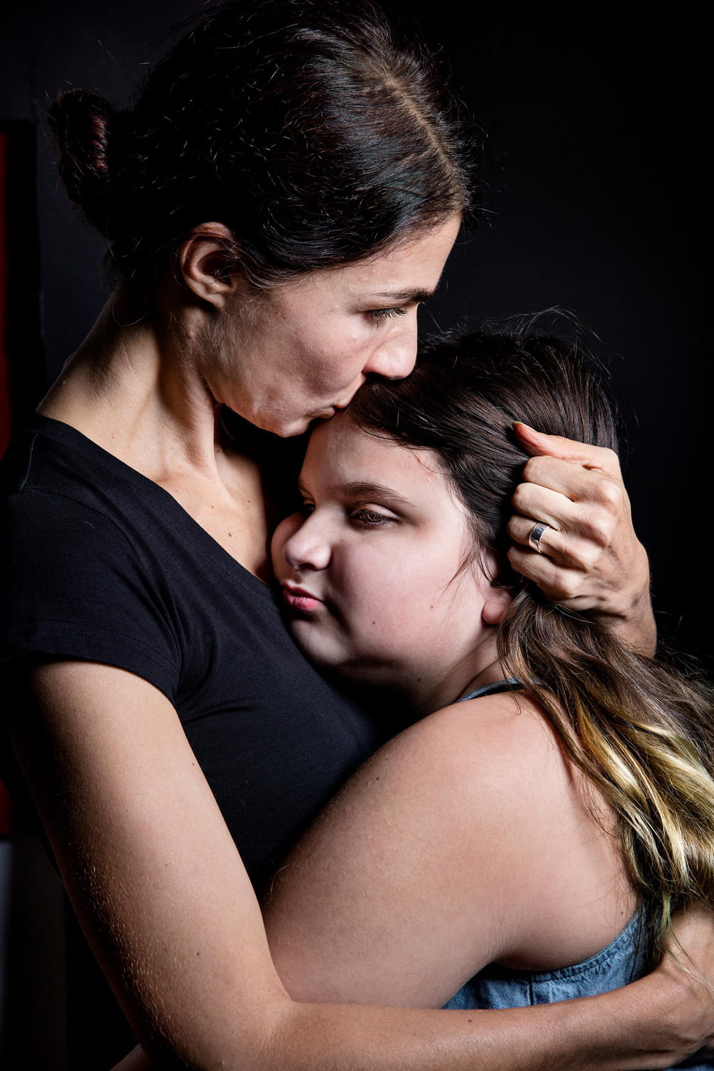 Photo of two human figures, a woman and her daughter hugging each other. 