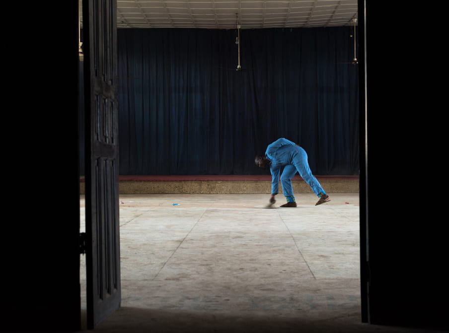 Photo of a man in a blue outfit sweeping the floor