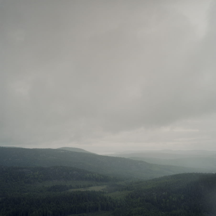 Photograph of a greyish landscape with hills and low hanging grey clouds.