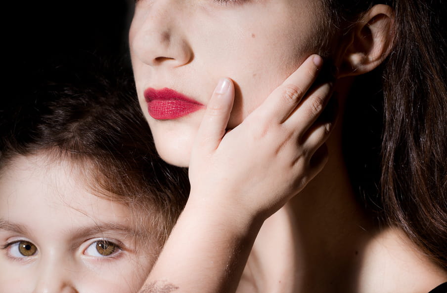 Close up photo of a young girl caressing her mother