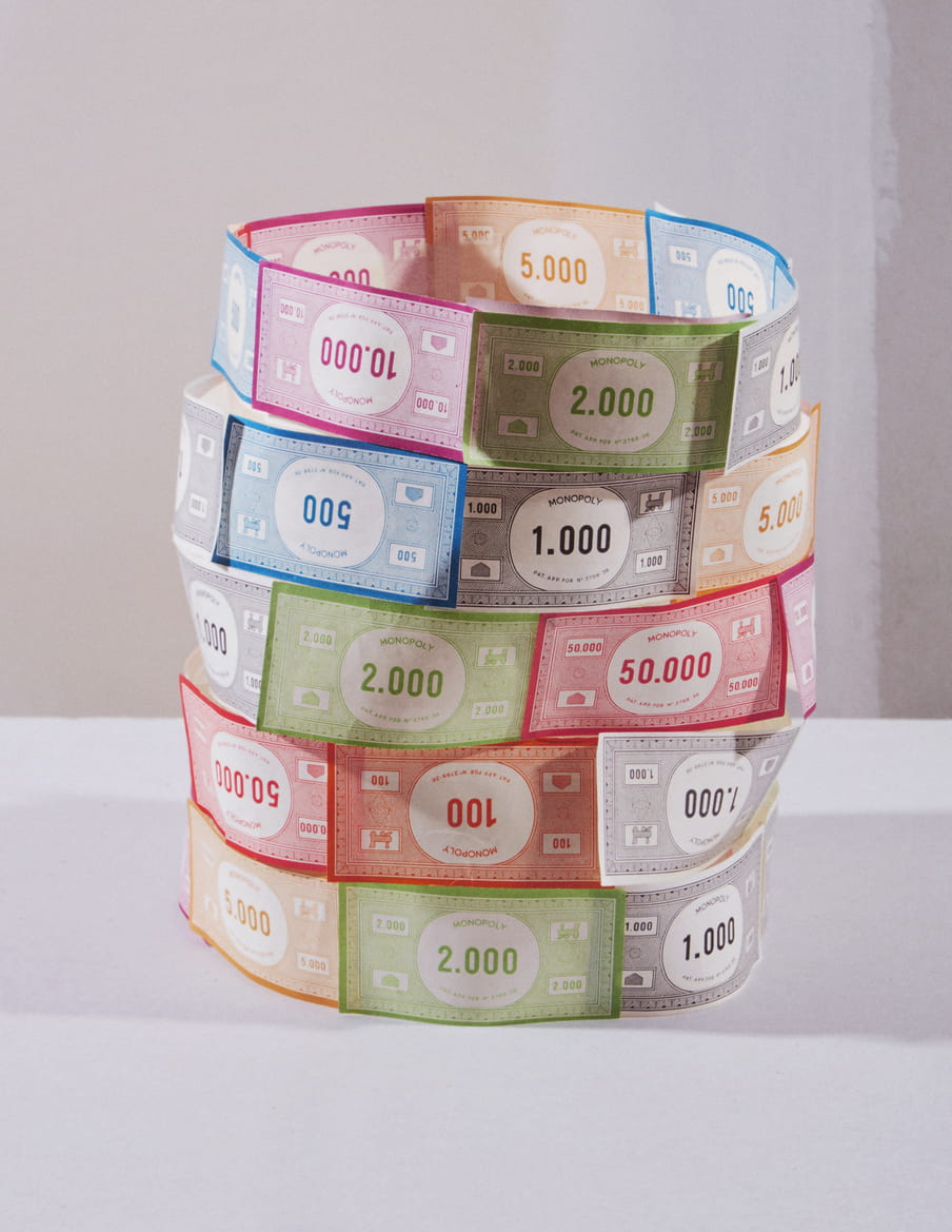 Colourful Monopoly paper currency are arranged in a delicate cylindric way. 