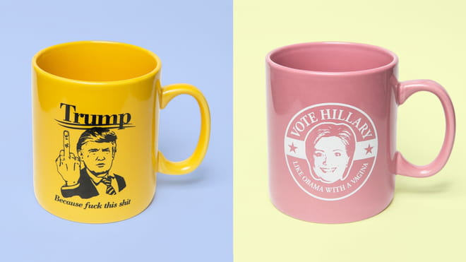Two cups, one yellow with an cartoon of Trump giving the finger with the text 'because fuck this shit', one pink one with 'Vote Hillary, like Obama with a vagina'