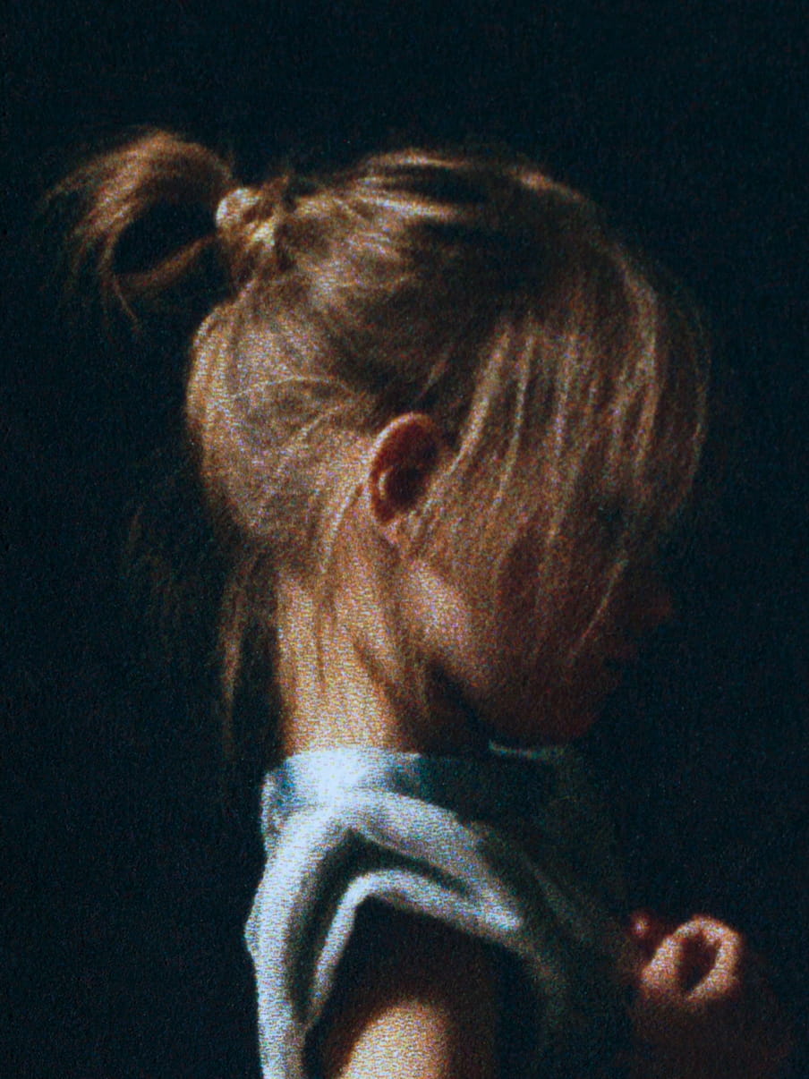 Photo, close up of a girls head, long hair in a bun, wearing a blue dress