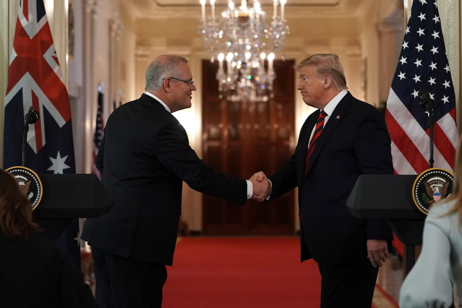 Two men wearing suits are shaking hands.