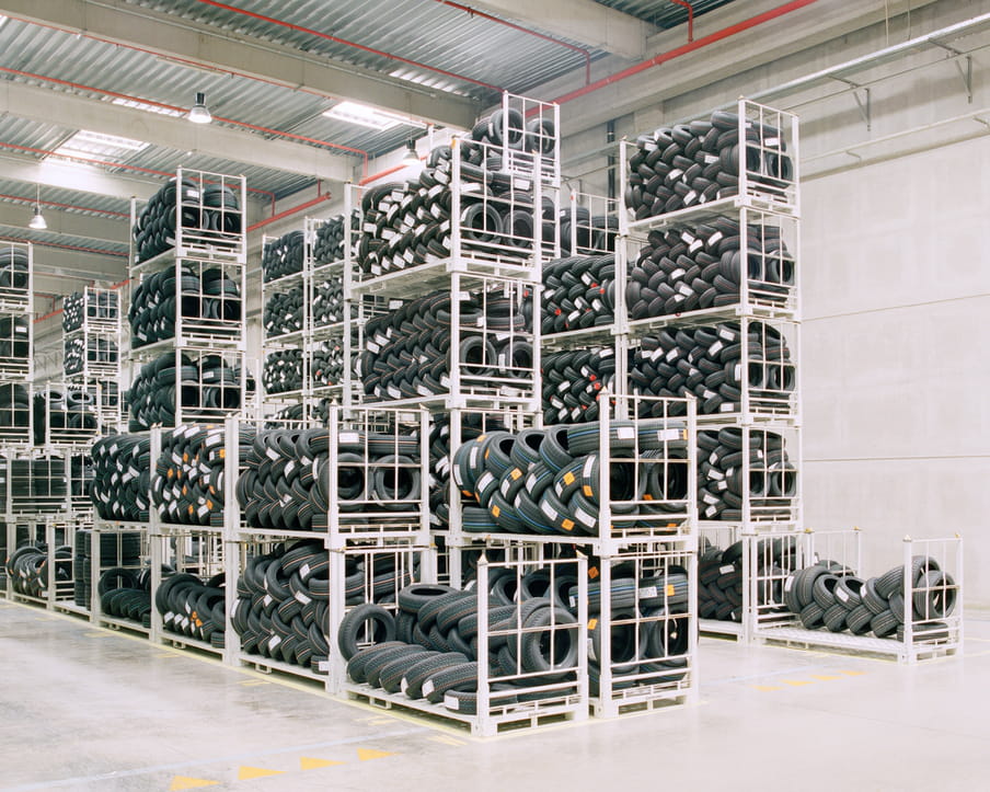 Colour photograph of a warehouse showing shelves with piles of tires.