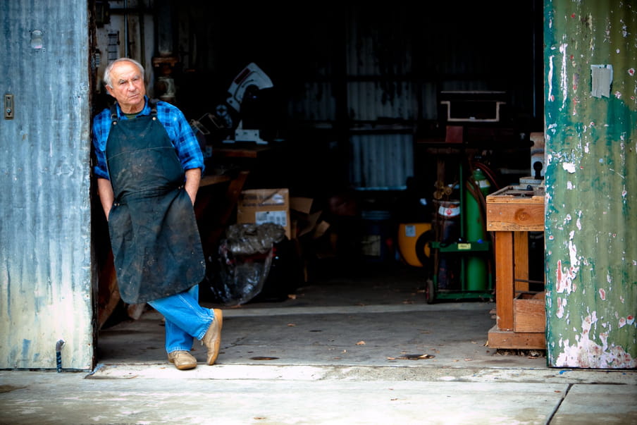 Photo of an older man standing in his workshop